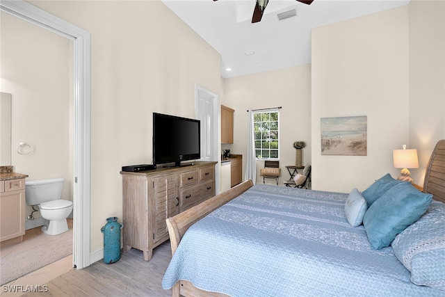 bedroom featuring light hardwood / wood-style floors, lofted ceiling, ceiling fan, and ensuite bath