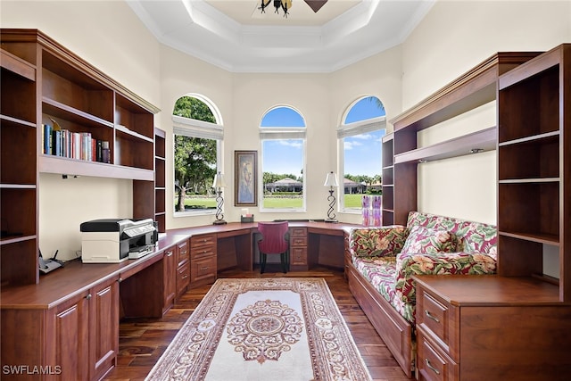 unfurnished office with ornamental molding, dark wood-type flooring, built in desk, and a raised ceiling