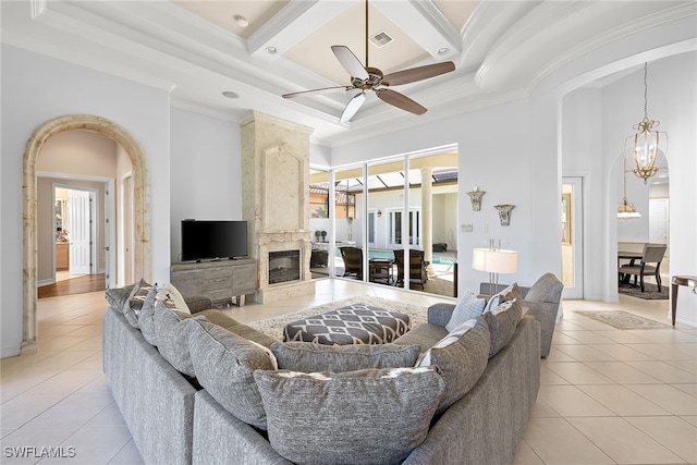 living room featuring beam ceiling, a wealth of natural light, light tile patterned floors, and ceiling fan with notable chandelier