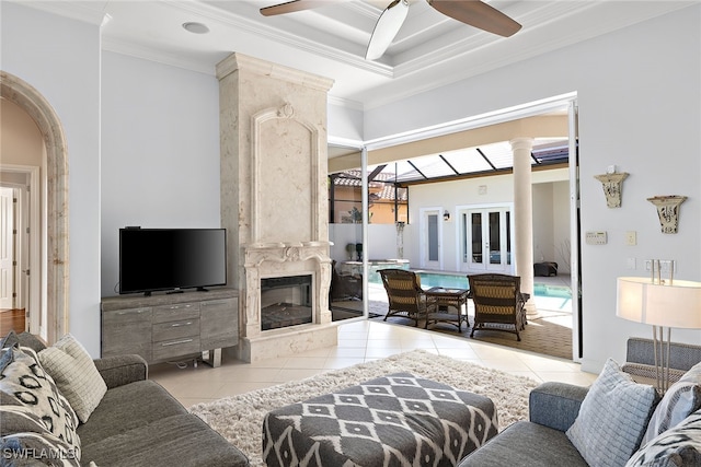 living room with ceiling fan, light tile patterned floors, ornamental molding, and a fireplace