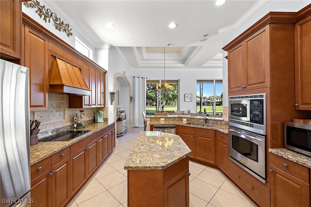 kitchen with stainless steel appliances, sink, light stone countertops, a center island, and pendant lighting