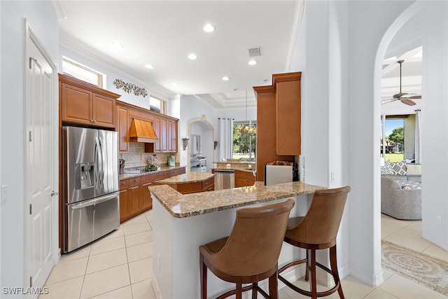 kitchen featuring kitchen peninsula, appliances with stainless steel finishes, light stone countertops, ceiling fan, and decorative light fixtures