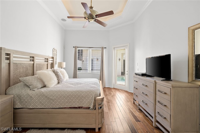 bedroom featuring dark hardwood / wood-style flooring, access to exterior, ceiling fan, a raised ceiling, and crown molding