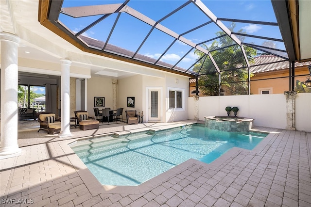 view of pool with glass enclosure, a patio area, and an in ground hot tub