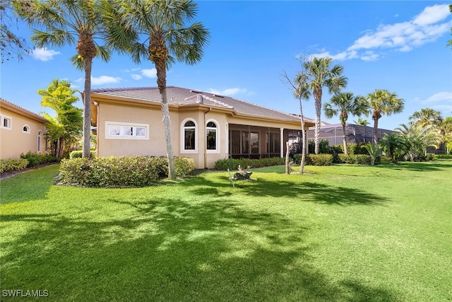 rear view of house featuring a lawn and a sunroom