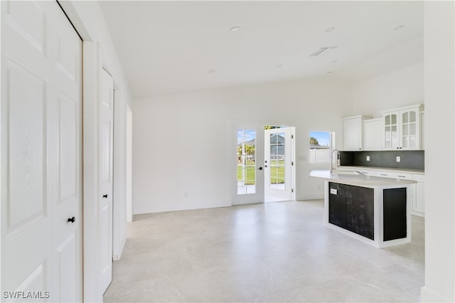 kitchen featuring a center island with sink, vaulted ceiling, white cabinets, decorative backsplash, and sink