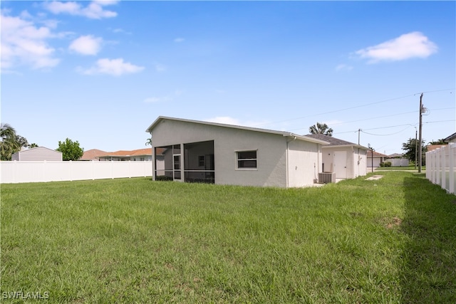 back of property featuring central air condition unit, a sunroom, and a lawn