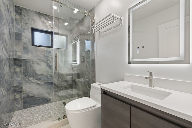 bathroom featuring vanity, a shower with shower door, and toilet