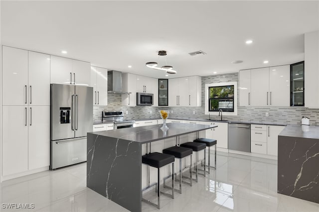 kitchen featuring stainless steel appliances, a center island, white cabinets, and wall chimney exhaust hood