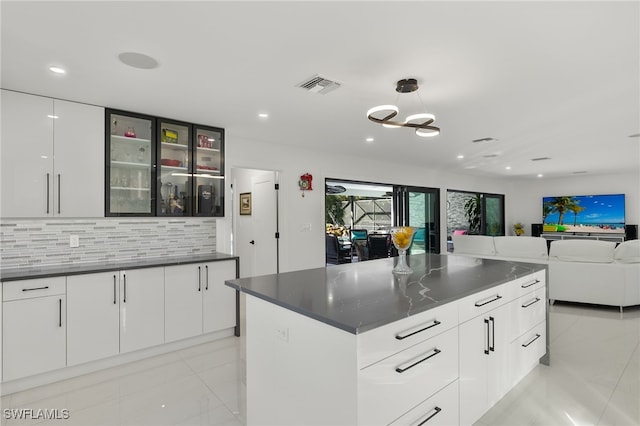 kitchen with white cabinetry, decorative backsplash, decorative light fixtures, and a center island