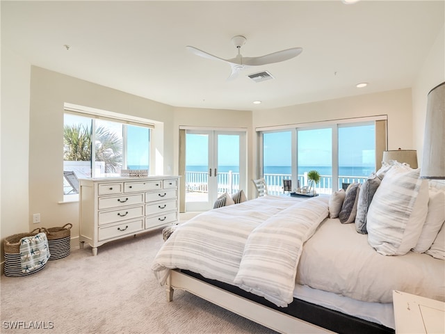 bedroom with light carpet, french doors, a water view, ceiling fan, and access to exterior