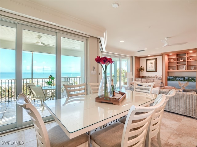 dining area featuring ceiling fan and a water view