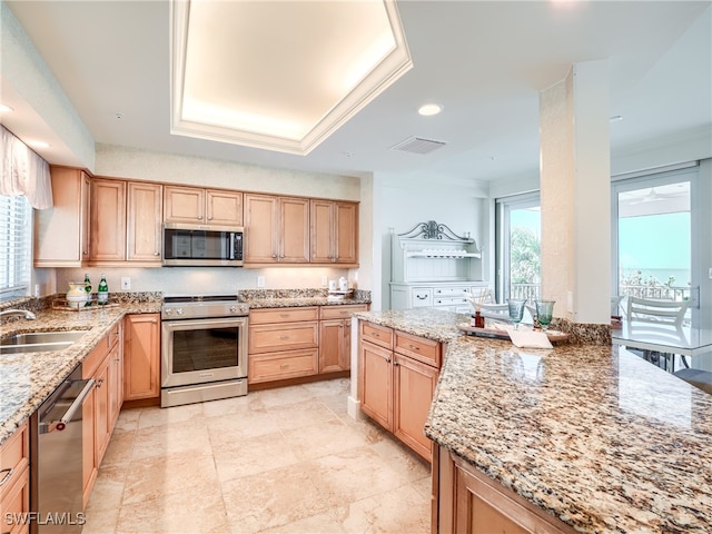 kitchen with light stone countertops, ornamental molding, stainless steel appliances, sink, and light brown cabinets