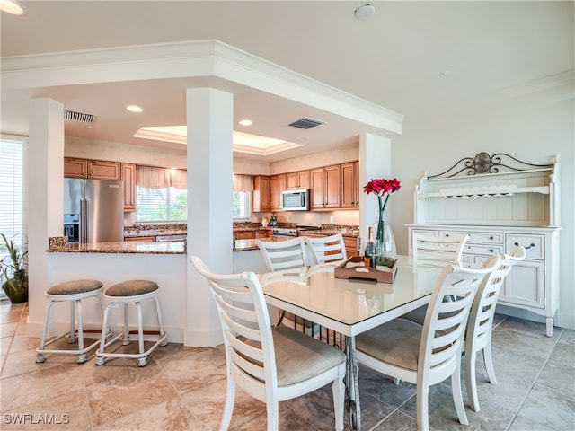 dining space featuring a raised ceiling and crown molding