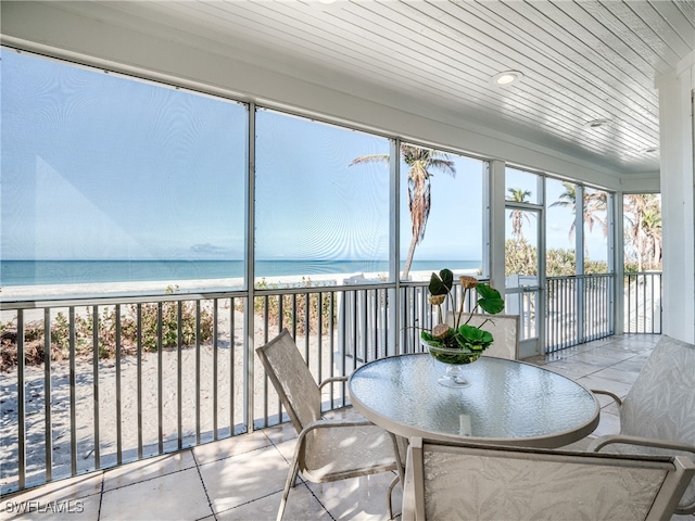 unfurnished sunroom with a water view, wooden ceiling, and a view of the beach