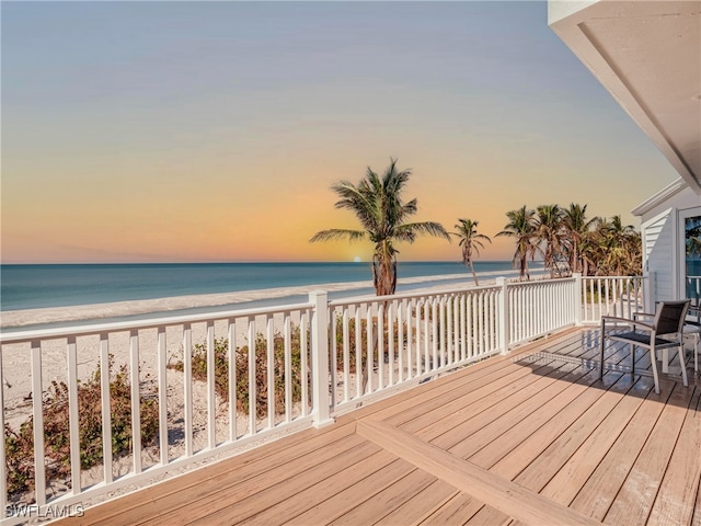 deck at dusk with a water view and a beach view