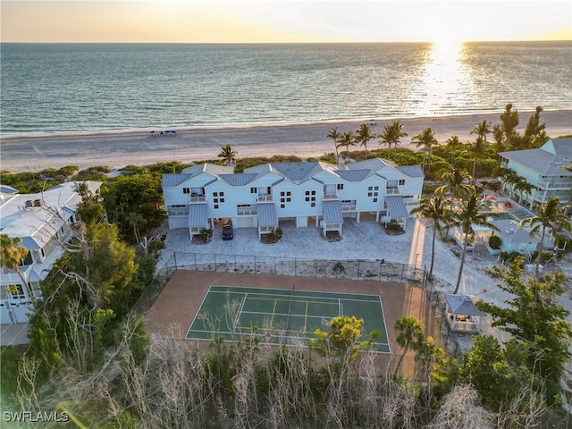 aerial view at dusk with a water view and a view of the beach