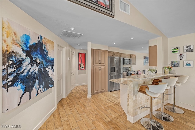 kitchen with a breakfast bar area, kitchen peninsula, light wood-type flooring, and appliances with stainless steel finishes