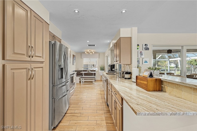 kitchen with light stone countertops, sink, light wood-type flooring, and stainless steel appliances