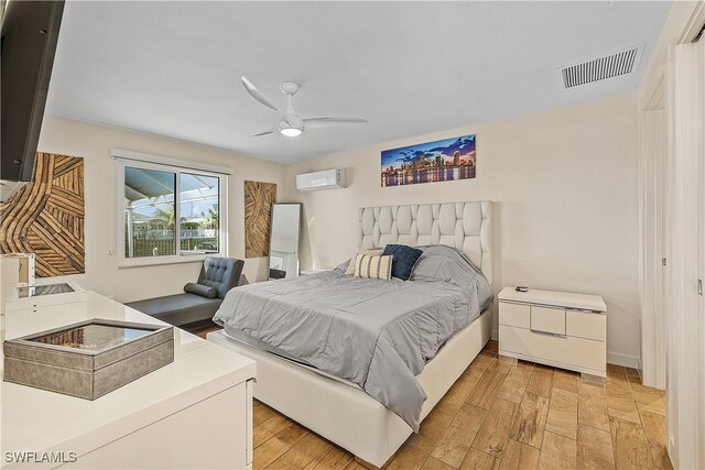 bedroom with ceiling fan, a wall unit AC, and light hardwood / wood-style flooring