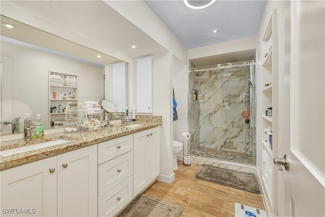 bathroom featuring wood-type flooring, vanity, toilet, and a shower with door