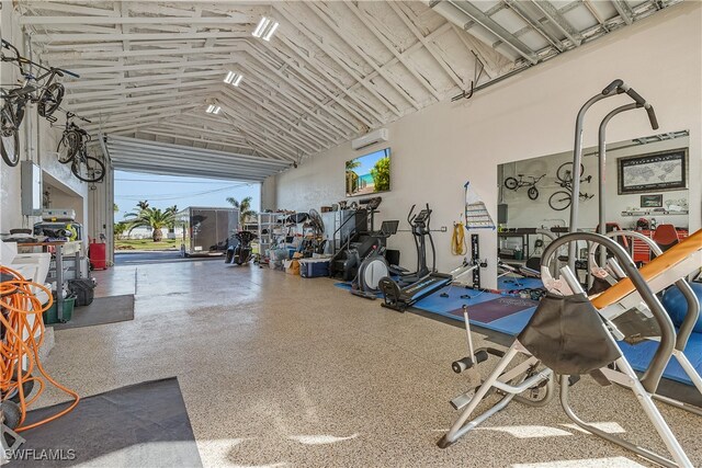 exercise room with high vaulted ceiling and a wall mounted AC