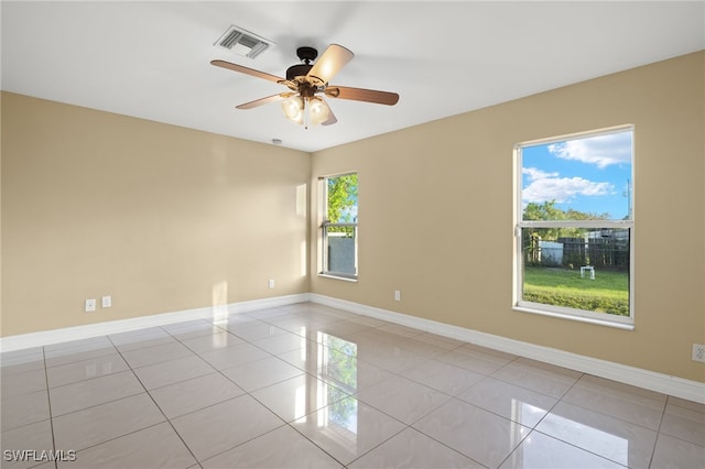 tiled spare room with a wealth of natural light and ceiling fan