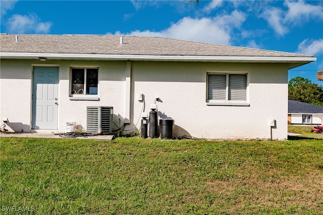 back of house with cooling unit and a lawn