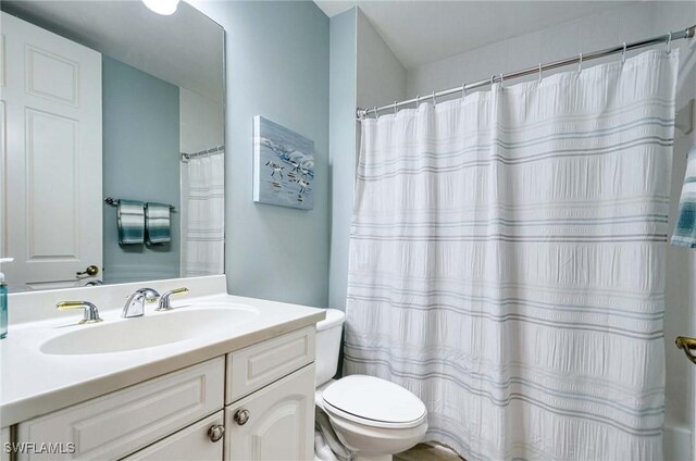 bathroom with curtained shower, vanity, and toilet