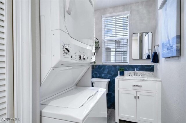 washroom with stacked washer / drying machine and sink