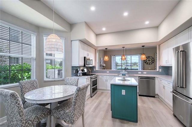 kitchen with a center island, hanging light fixtures, tasteful backsplash, white cabinetry, and stainless steel appliances