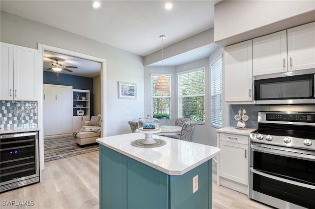 kitchen with appliances with stainless steel finishes, white cabinetry, and beverage cooler