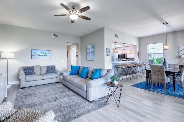 living room with light wood-type flooring and ceiling fan