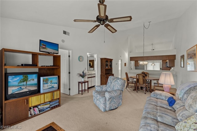 carpeted living area featuring ceiling fan, visible vents, and high vaulted ceiling