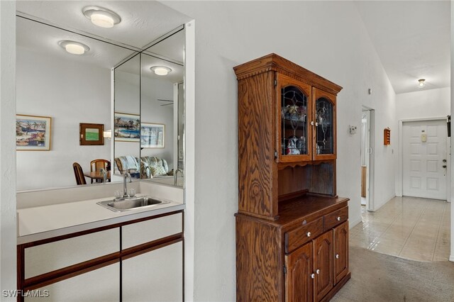 interior space with light tile patterned floors, light colored carpet, indoor wet bar, and a sink