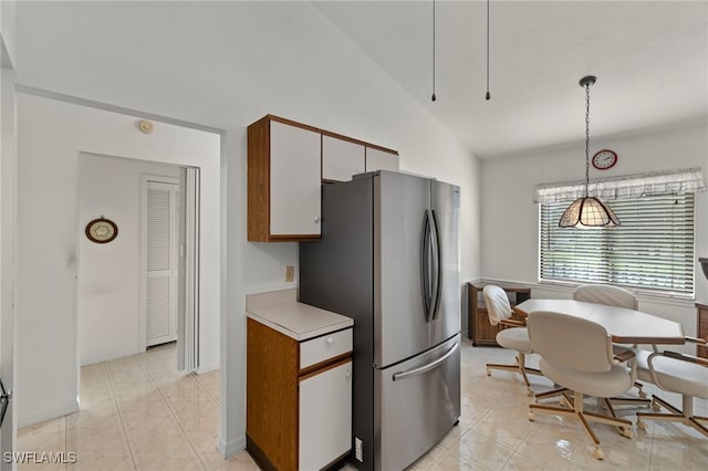 kitchen with white cabinets, hanging light fixtures, stainless steel refrigerator, and vaulted ceiling