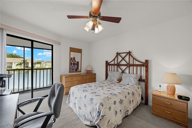 carpeted bedroom featuring access to exterior, ceiling fan, and a water view