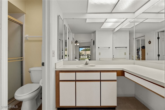 bathroom featuring ceiling fan, toilet, vanity, and walk in shower