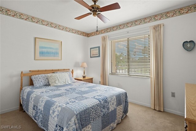 carpeted bedroom with ceiling fan and baseboards