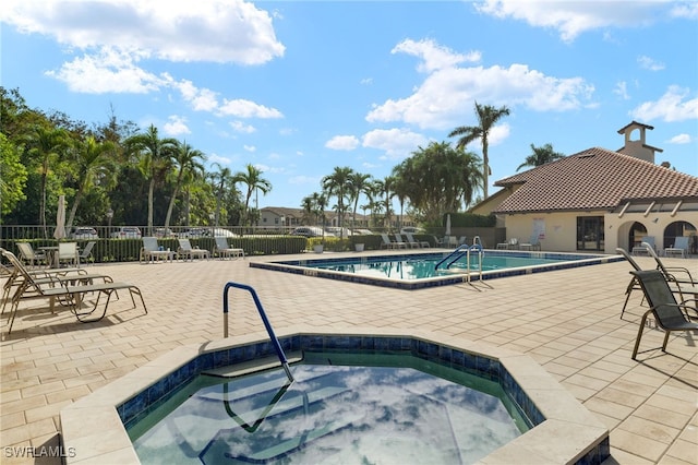 community pool featuring a community hot tub, a patio, and fence