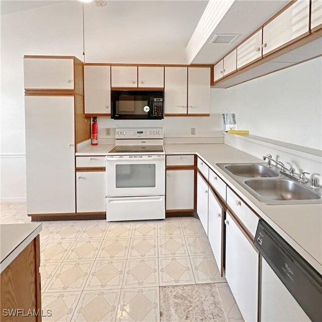 kitchen with white cabinets, white appliances, light countertops, and a sink