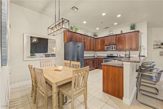 kitchen featuring decorative light fixtures, light tile patterned floors, dark stone counters, appliances with stainless steel finishes, and sink