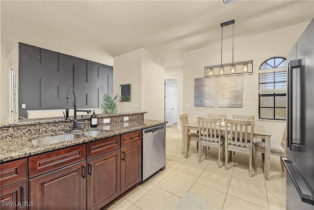 kitchen featuring dark stone countertops, appliances with stainless steel finishes, hanging light fixtures, sink, and light tile patterned flooring