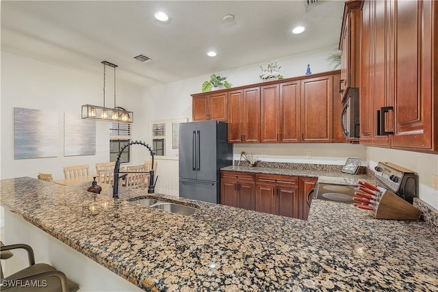 kitchen featuring sink, a kitchen bar, kitchen peninsula, hanging light fixtures, and appliances with stainless steel finishes