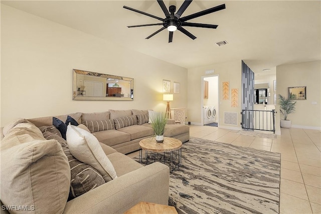 tiled living room with ceiling fan and separate washer and dryer