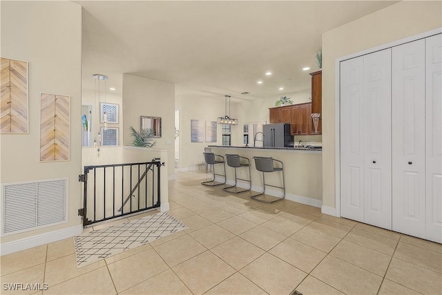 kitchen featuring high end fridge, pendant lighting, a kitchen breakfast bar, and light tile patterned floors