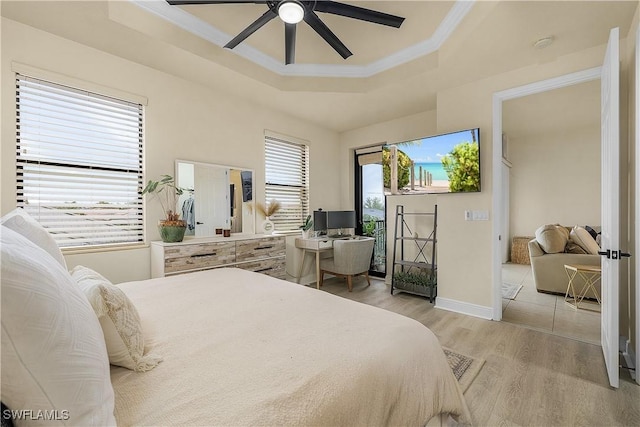 bedroom featuring ceiling fan, a tray ceiling, and light wood-type flooring