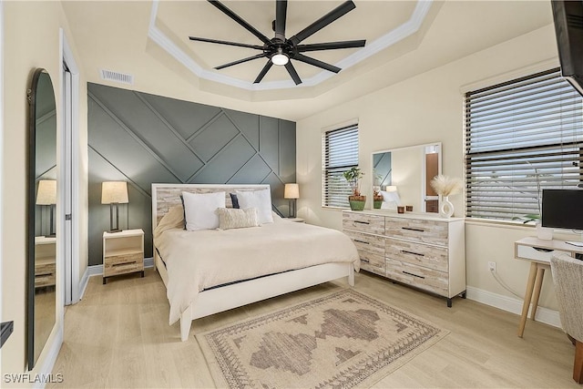 bedroom with a raised ceiling, ceiling fan, crown molding, and light hardwood / wood-style floors