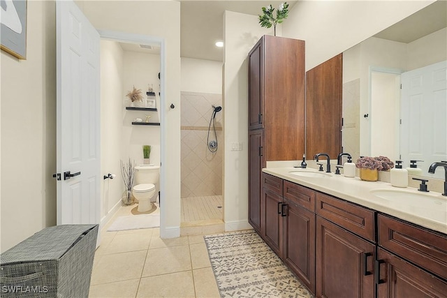 bathroom featuring a tile shower, toilet, vanity, and tile patterned floors