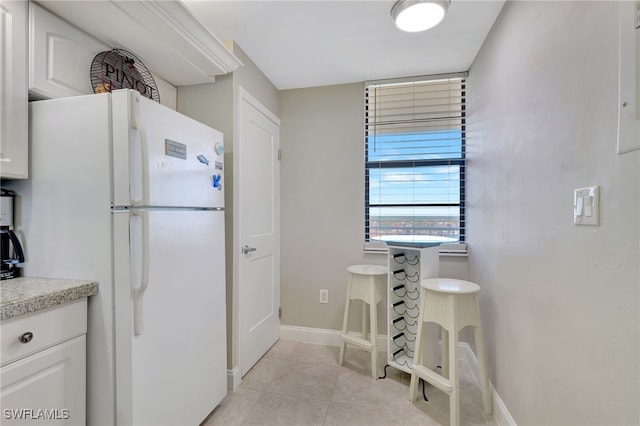 kitchen with white cabinets, white fridge, and light tile patterned floors